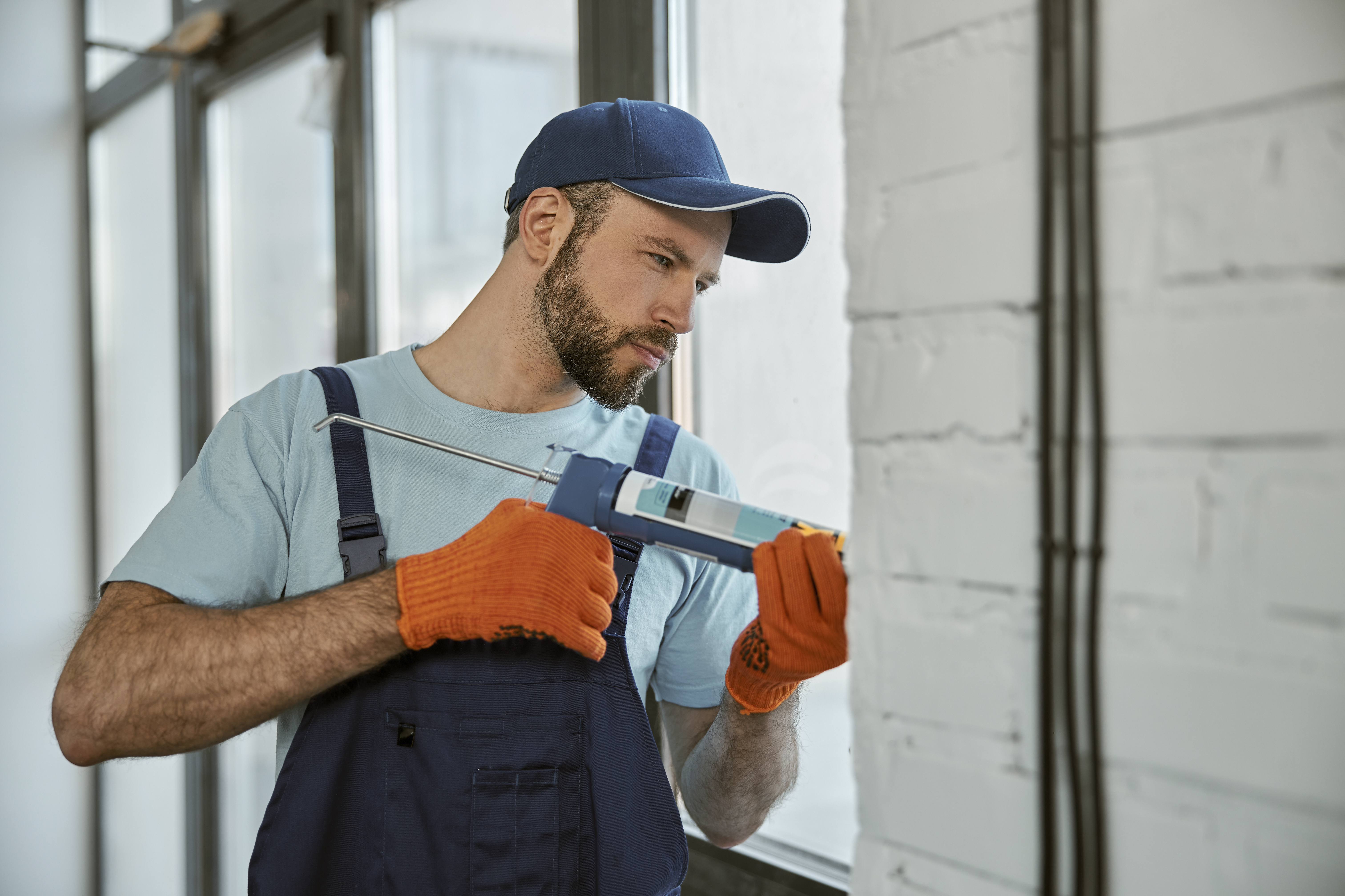 bearded-young-man-repairing-window-with-