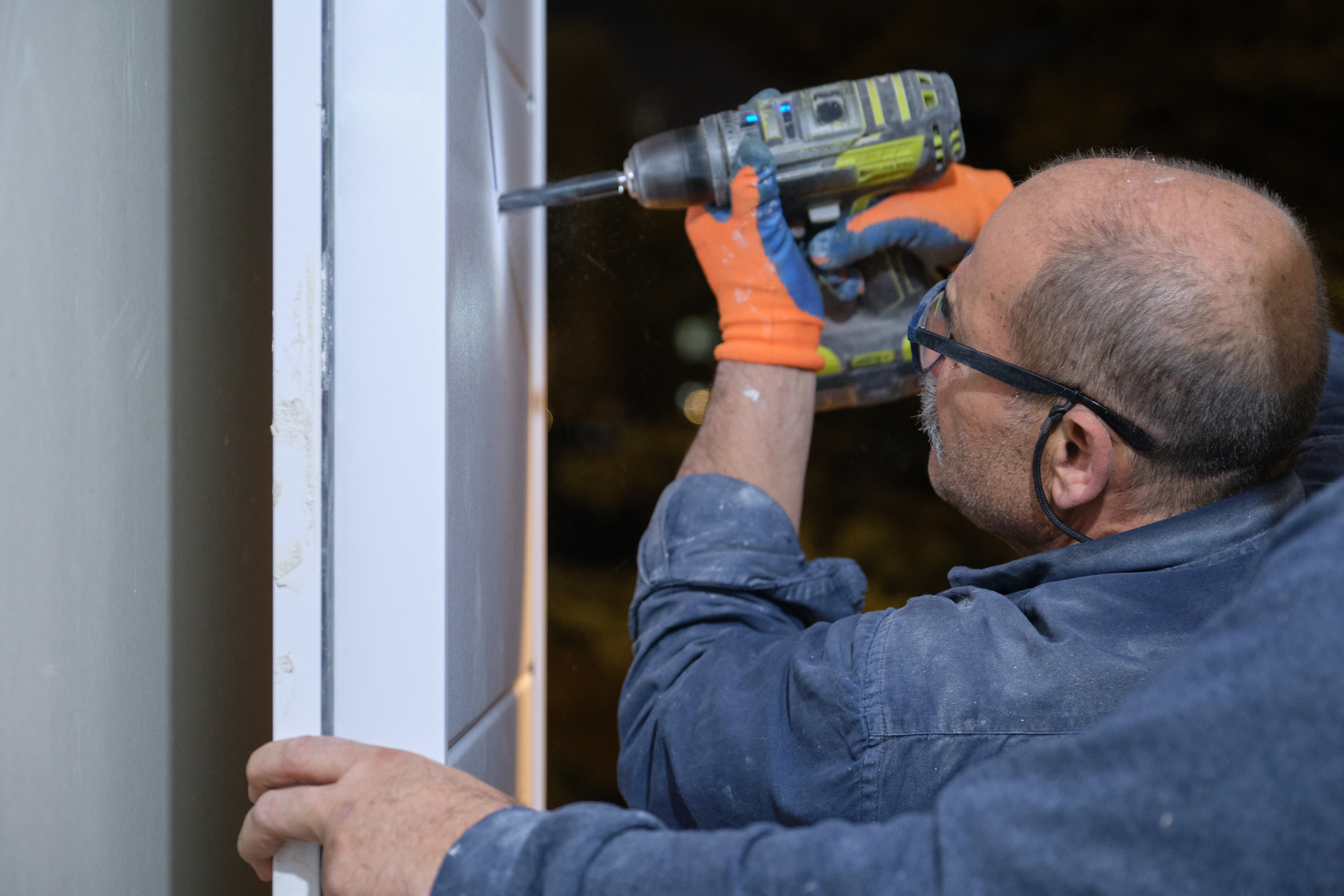 senior-worker-installing-a-peephole-in-a